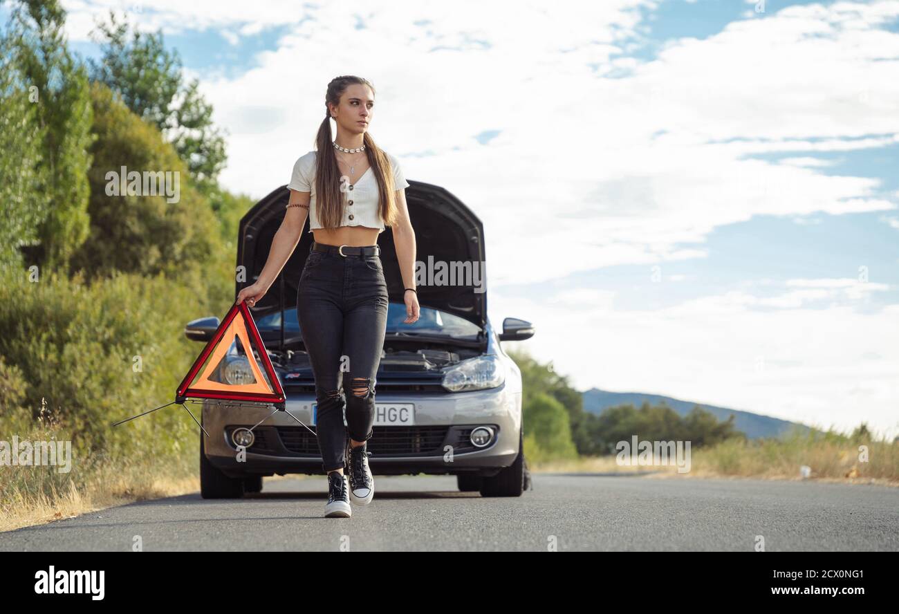 Ragazza che mette guasto segnalazione triangolo auto Foto Stock
