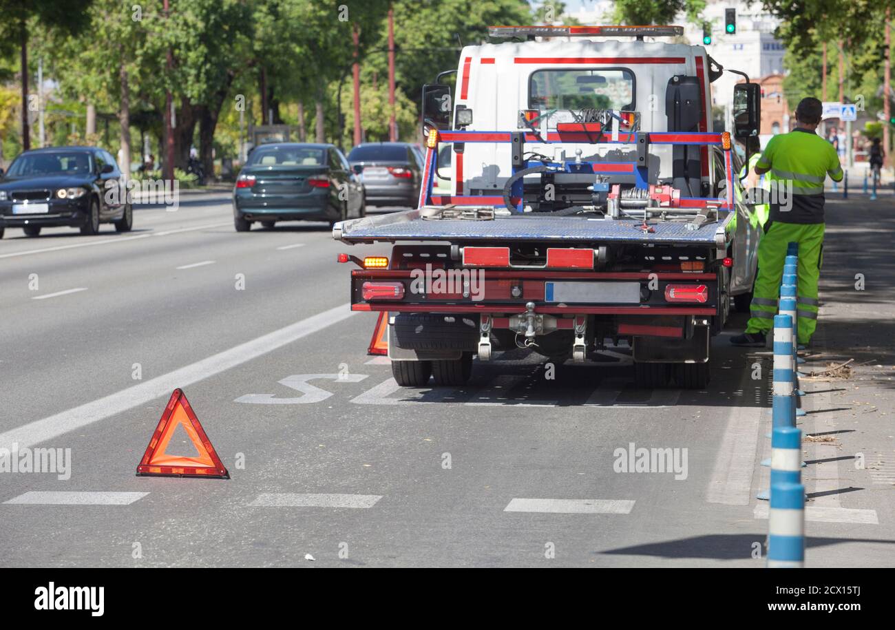 Triangolo pieghevole di avvertenza posizionato prima del cingolo di traino. Scena urbana Foto Stock