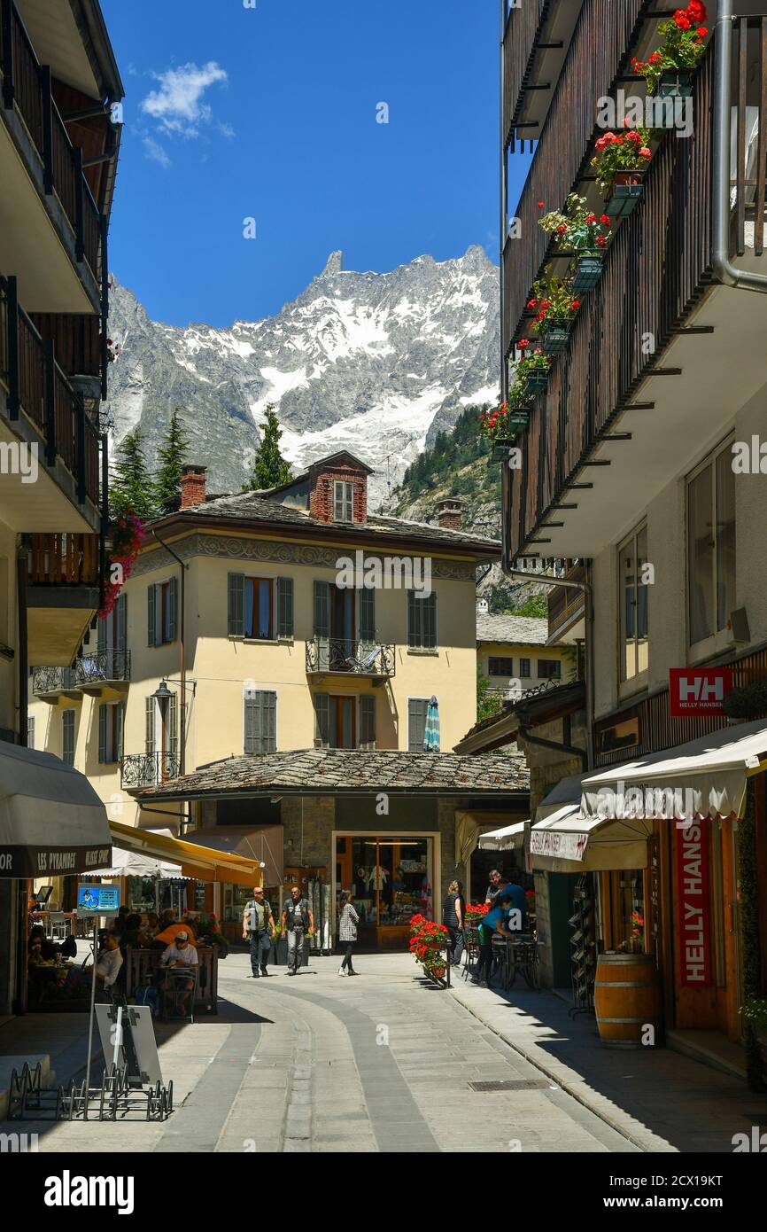 Vista sulla strada della famosa meta turistica delle Alpi italiane con persone a piedi e il massiccio del Monte Bianco in estate, Courmayeur, Aosta, Italia Foto Stock