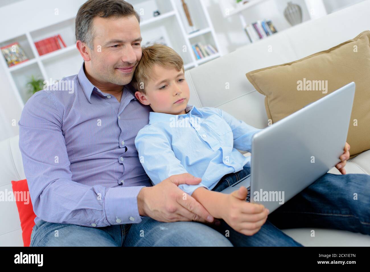 Uomo e bambino sul divano guardando il computer portatile Foto Stock