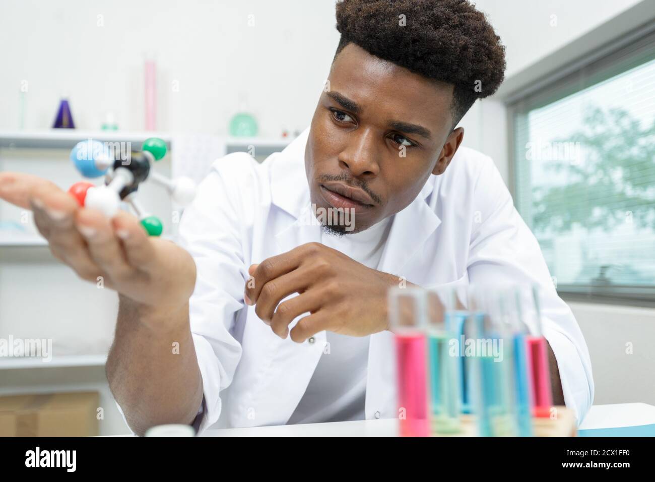 scienziato in un camice di laboratorio che tiene un modello molecolare Foto Stock