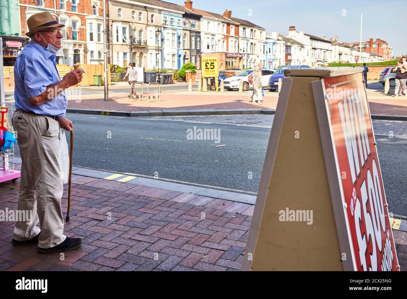 Uomo anziano che mangia un gelato con la sua copertura facciale sotto il mento Foto Stock