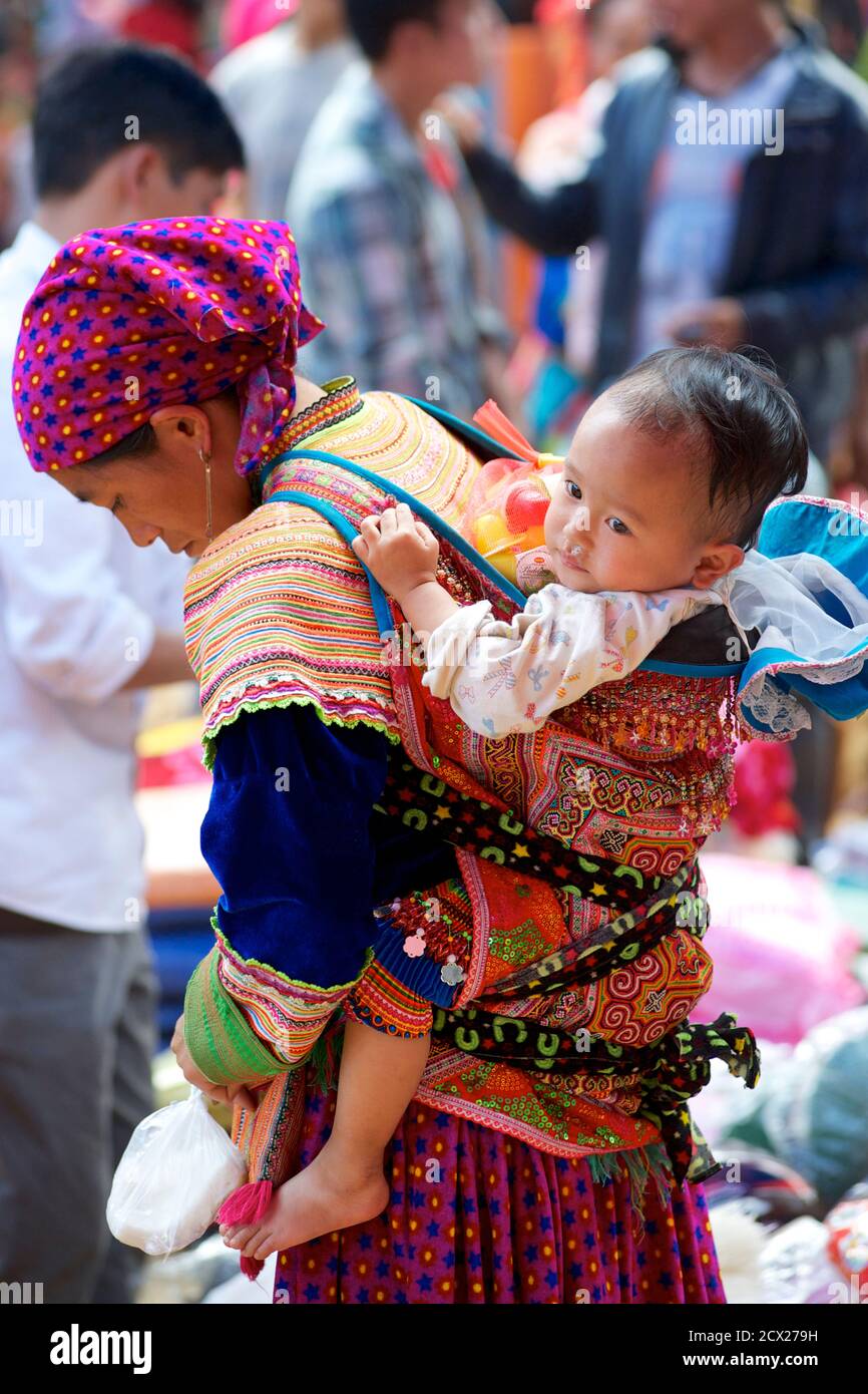 Donna Hmong con bambino in baby carrier sulla schiena, Can Cau mercato, vicino Bac ha, Lao Cai Provincia, Vietnam Foto Stock