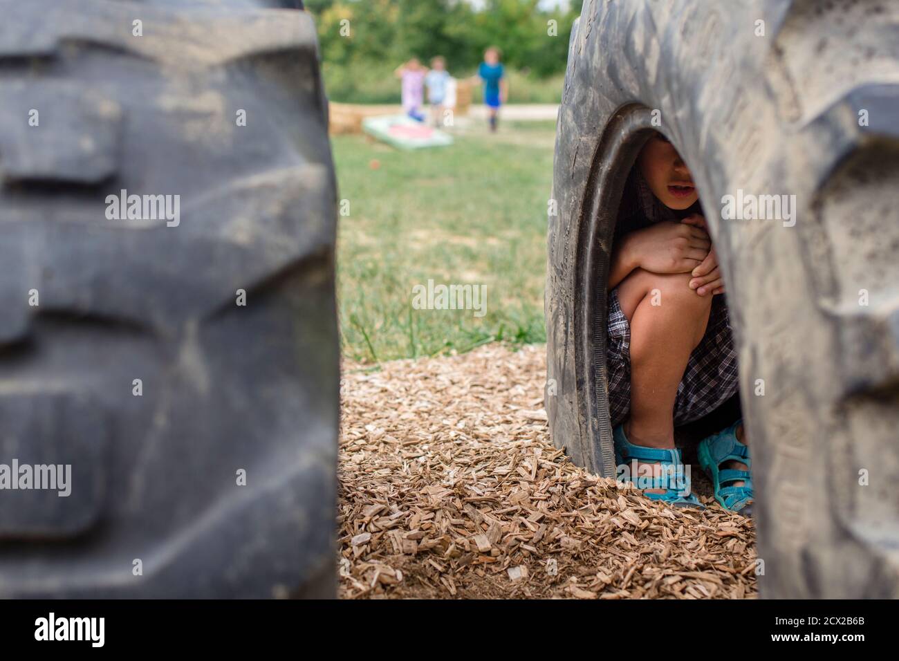 Un ragazzo si stucchi all'interno di un pneumatico su un parco giochi in gioco di hide-and-seek Foto Stock