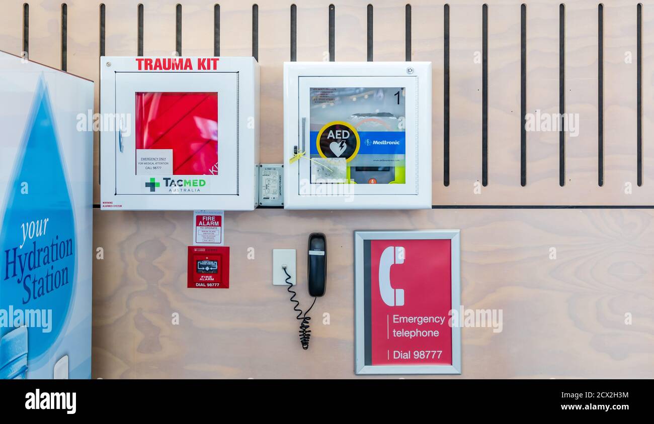 Un kit Trauma, defibrillatore (AED), pulsante di allarme antincendio e telefono di emergenza, montato a parete nel terminal passeggeri dell'aeroporto internazionale di Auckland, Nuova Zelanda Foto Stock