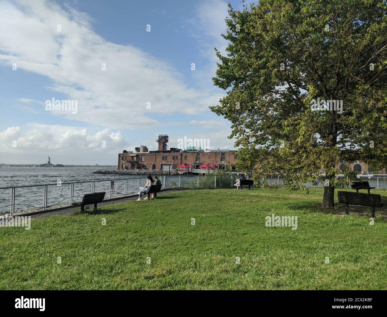 Panchine nel parco vicino all'acqua e vecchio industriale Struttura nel quartiere Red Hook di Brooklyn Foto Stock