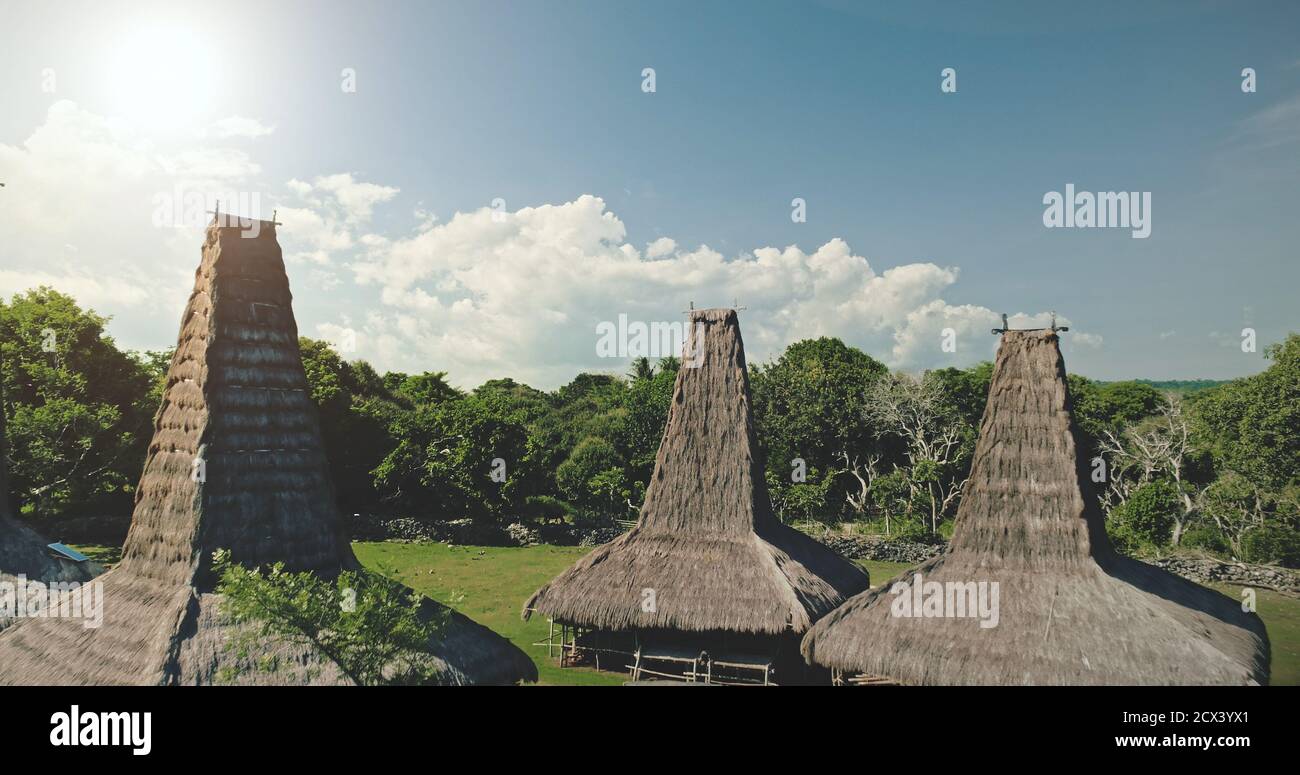 Case di villaggio tradizionale tetti closeup a tropicale paesaggio verde. Amazing ornately case tetti di Sumba Island, Indonesia. Attrazione Asia a foresta verde con valle erbosa Foto Stock