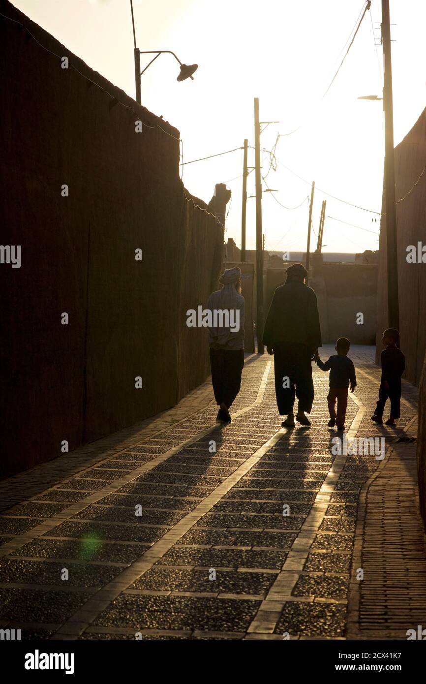 Uomini e bambini iraniani che camminano attraverso i vicoli di Yazd, Iran al tramonto. Foto Stock