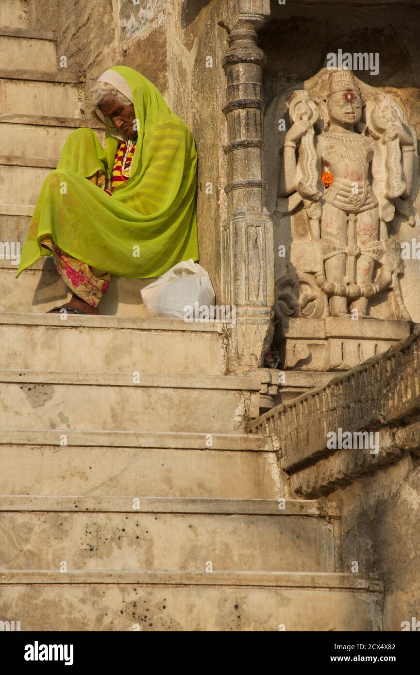 Donna anziana sui gradini del tempio. Fuori Jagdish Tempio, Udaipur, Rajasthan, India Foto Stock