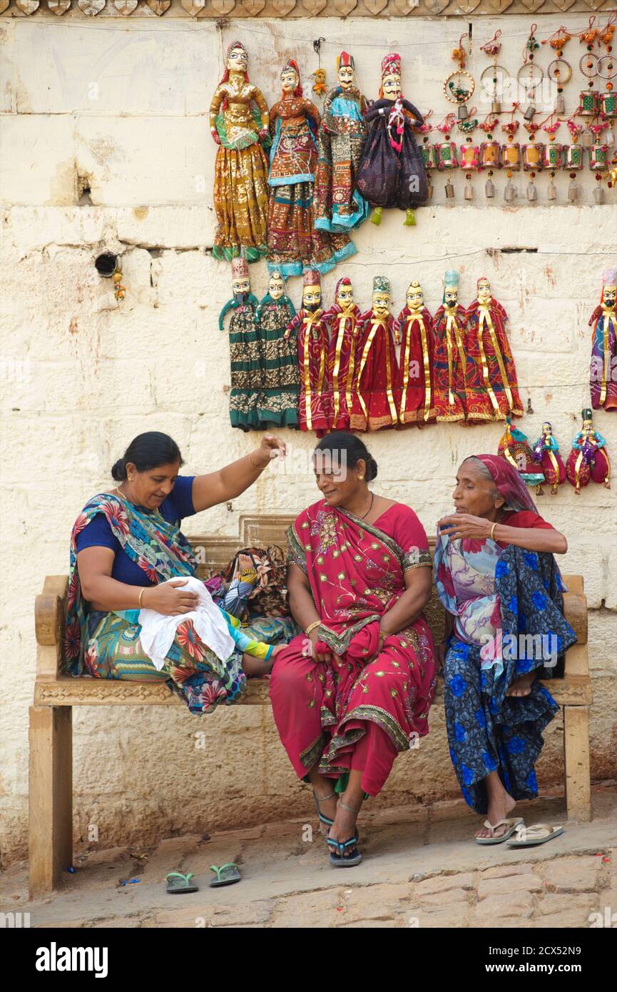 Donne indiane, una con bambino, su una panchina. Jaisalmer, Rajasthan, India Foto Stock