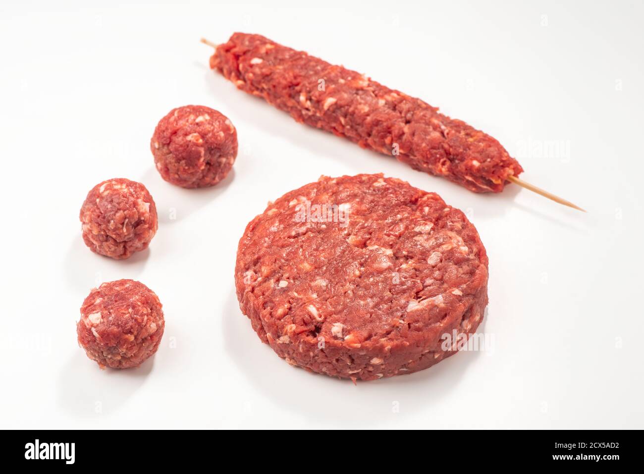 Primo piano su polpette grezze, patty e kebab su sfondo bianco Foto Stock