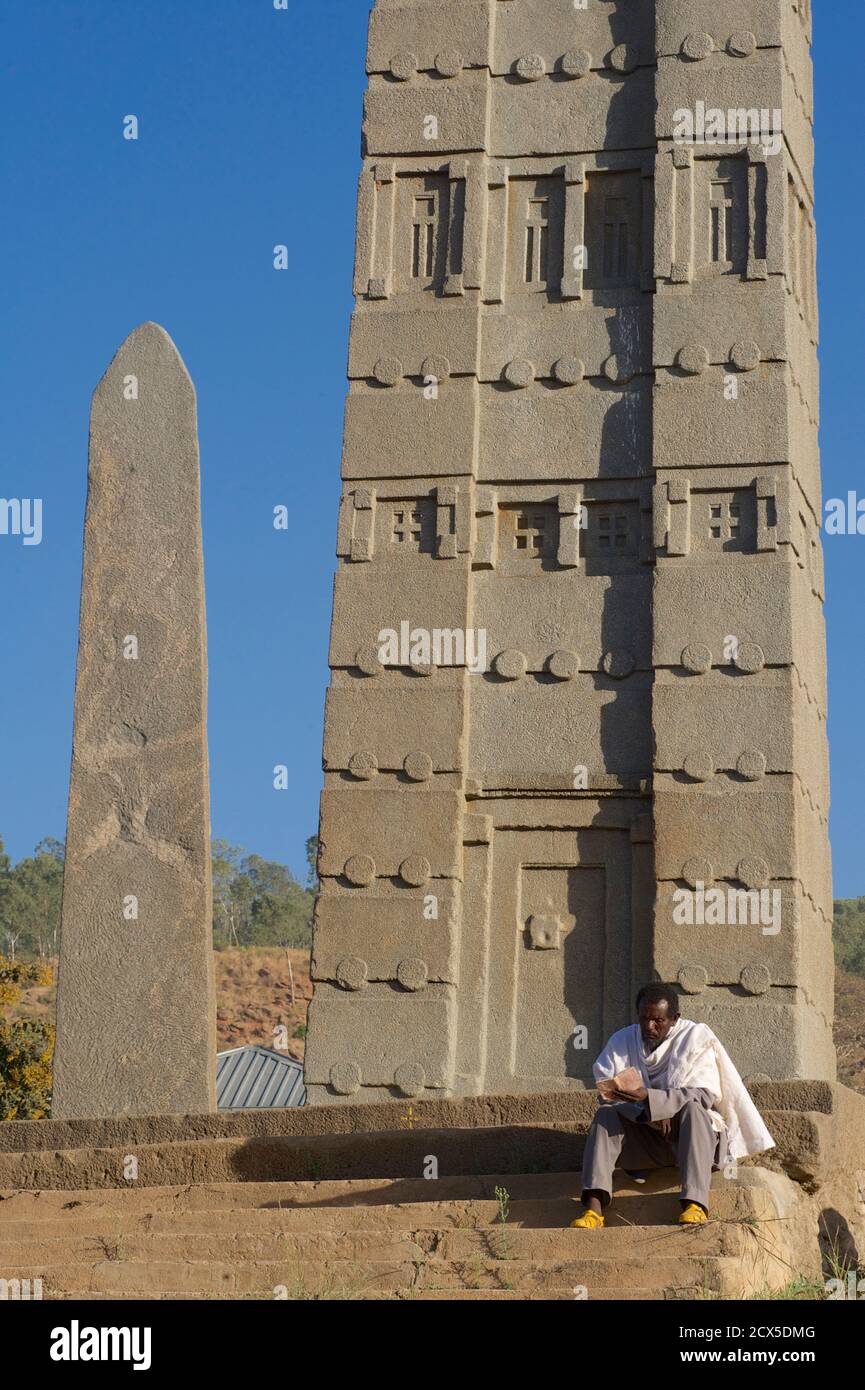 La Stela di Re Ezana è l'obelisco centrale che si trova ancora nel Parco delle Stele del Nord, nell'antica città di Axum, nell'Etiopia moderna. Libro di preghiera di lettura del Pilgrim etiope alla base dell'obelisco Foto Stock