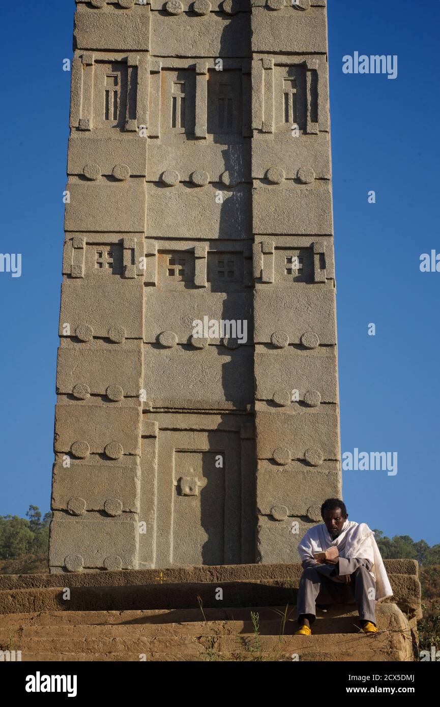 La Stela di Re Ezana è l'obelisco centrale che si trova ancora nel Parco delle Stele del Nord, nell'antica città di Axum, nell'Etiopia moderna. Libro di preghiera di lettura del Pilgrim etiope alla base dell'obelisco Foto Stock