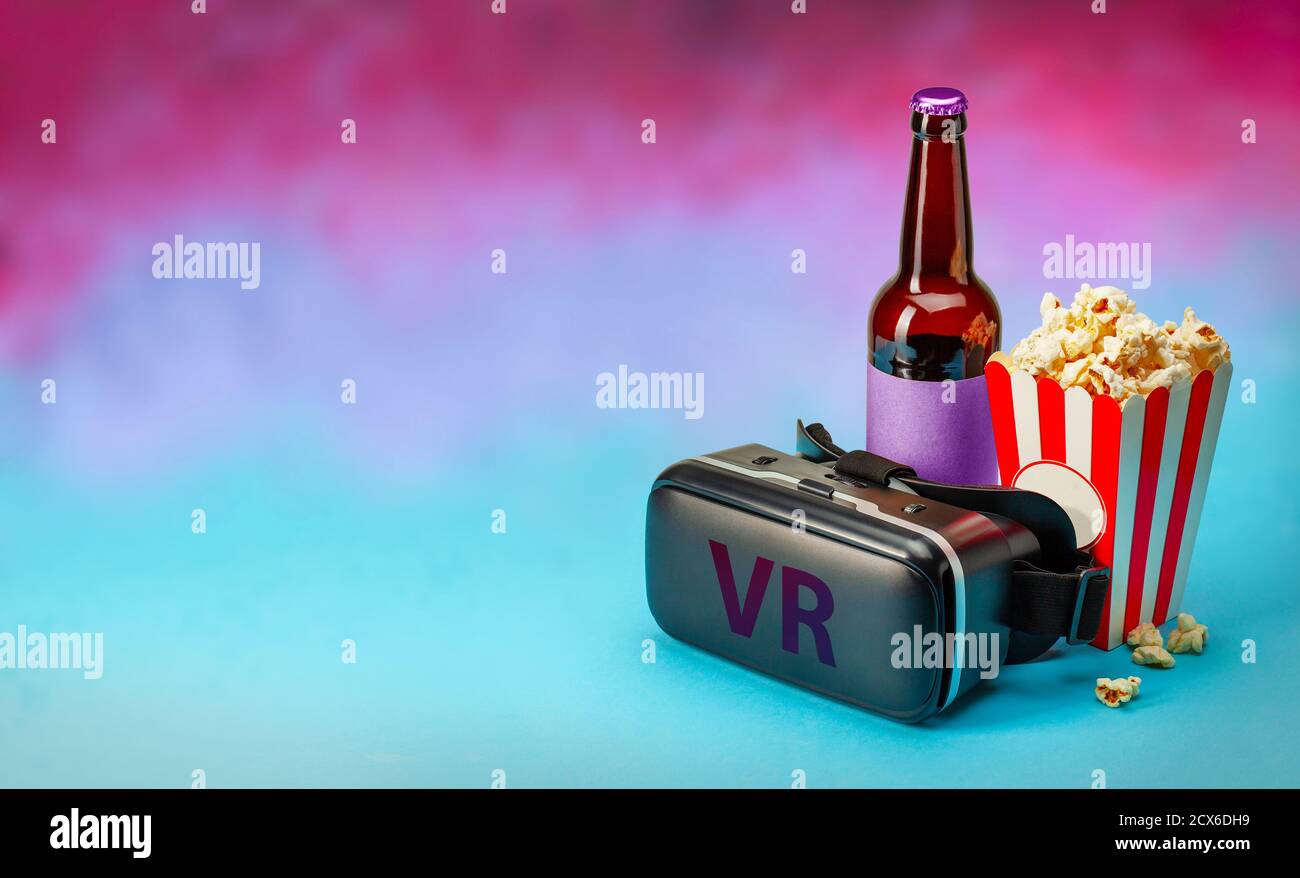 Film VR a casa. Occhiali VR casco e popcorn e bottiglia di birra su sfondo colorato. Spazio di copia per il testo Foto Stock
