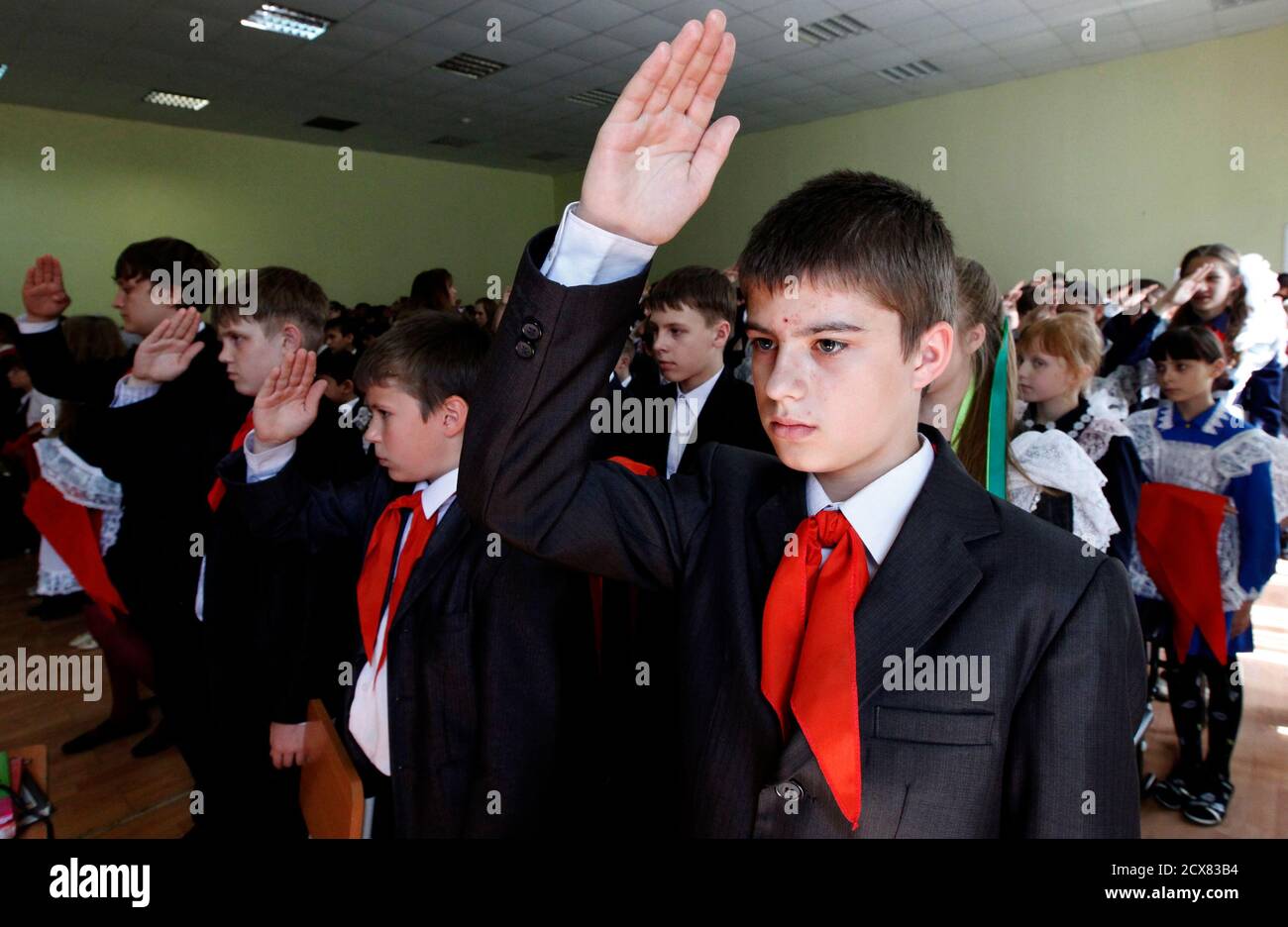 I bambini, che indossano i fazzoletti rossi, simbolo della Young Pioneer  Organization, salutano durante una cerimonia di inaugurazione di 55 membri  recentemente adottati il giorno del suo anniversario alla scuola-lyceum  numero 12