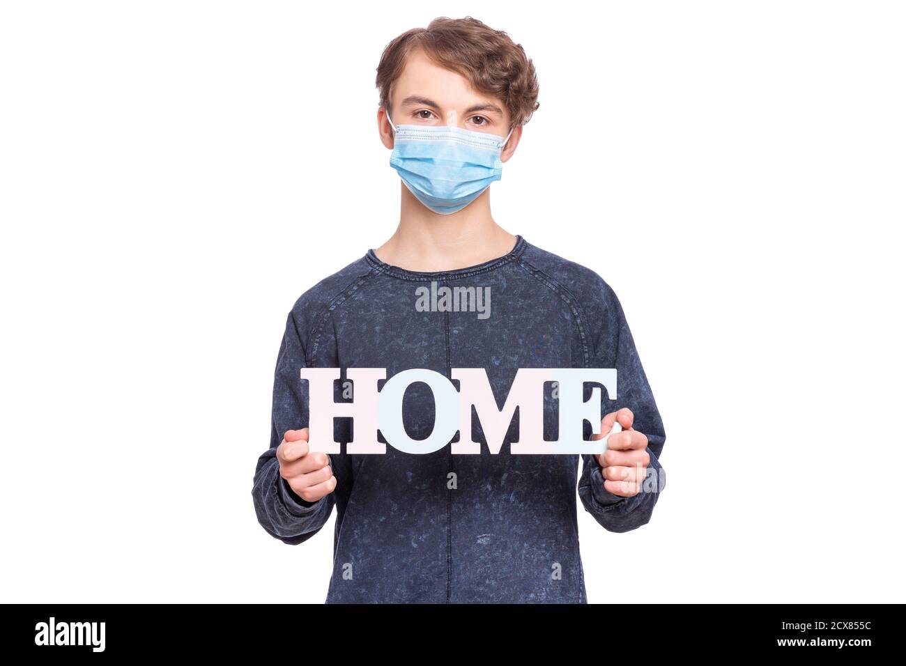 Quarantena di coronavirus. Bambino che indossa una maschera medica di protezione del viso, tiene parola Home - messaggio per le persone di rimanere a casa. COVID-19 - autoisolamento. Foto Stock