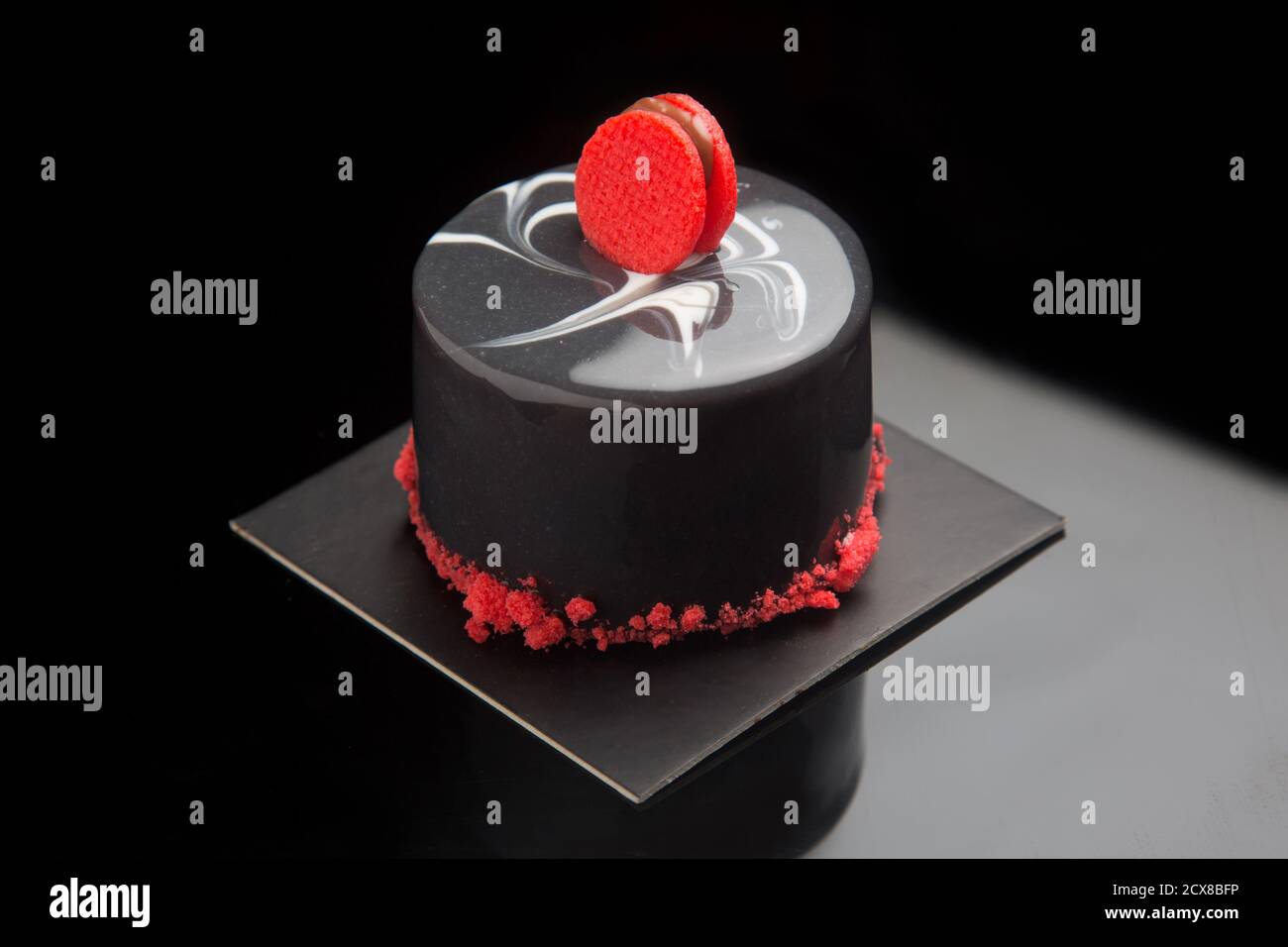 Torta individuale con smalto a specchio nero, su sfondo nero. Foto Stock