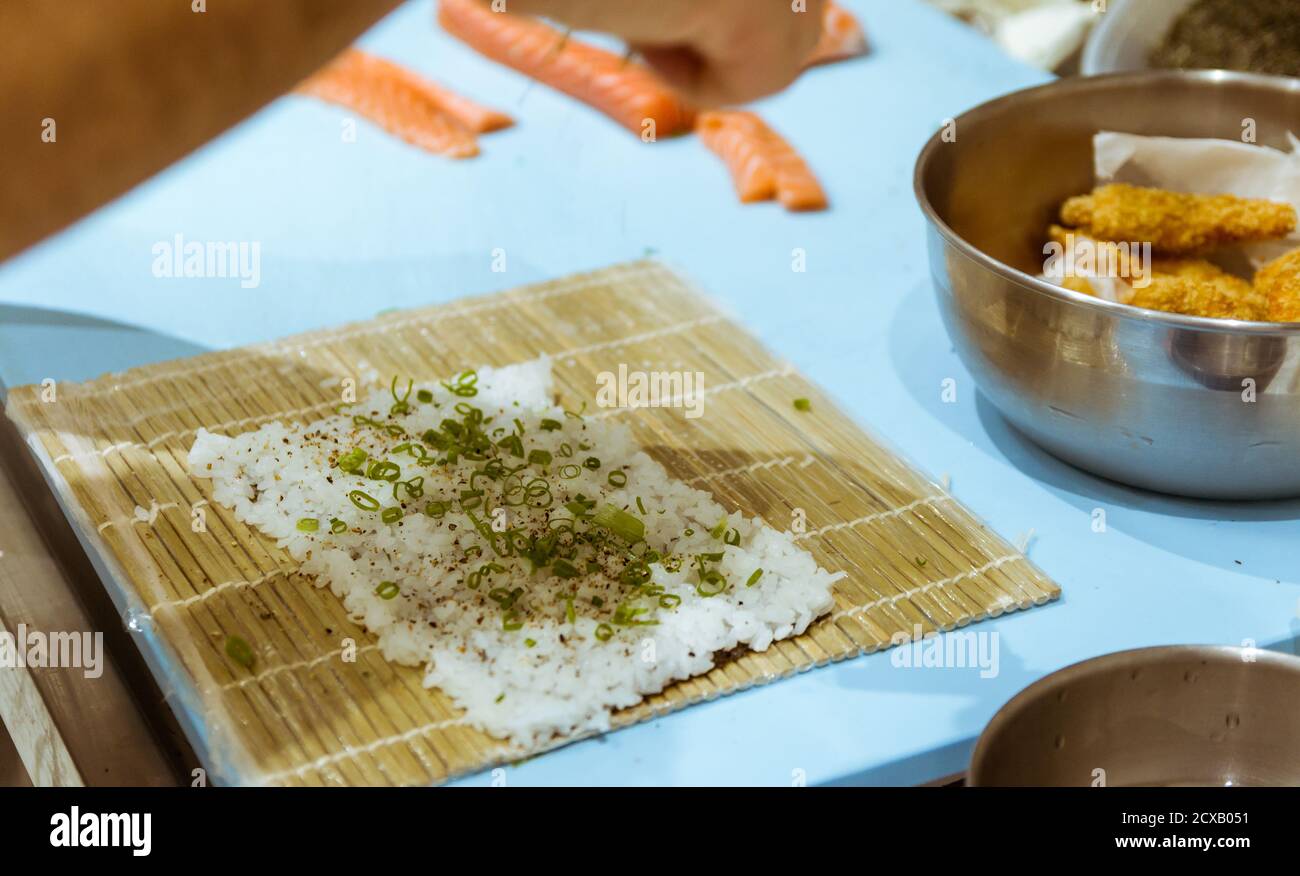 Primo piano di mani dello chef che preparano cibo giapponese. Chef giapponese che prepara sushi al ristorante. Giovane chef che prepara il tradizionale sushi giapponese sulla tavola da taglio. Foto Stock