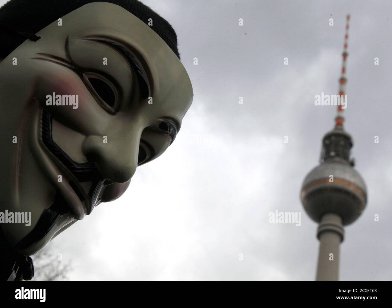 A protestor wearing Guy Fawkes masks participates in a demonstration next to the television tower against the Anti-Counterfeiting Trade Agreement (ACTA) in Berlin February 25, 2012. Protesters fear that ACTA, which aims to cut trademark theft and other online piracy, will curtail freedom of expression, curb their freedom to download movies and music for free and encourage Internet surveillance. REUTERS/Tobias Schwarz (GERMANY - Tags: POLITICS CIVIL UNREST) Foto Stock