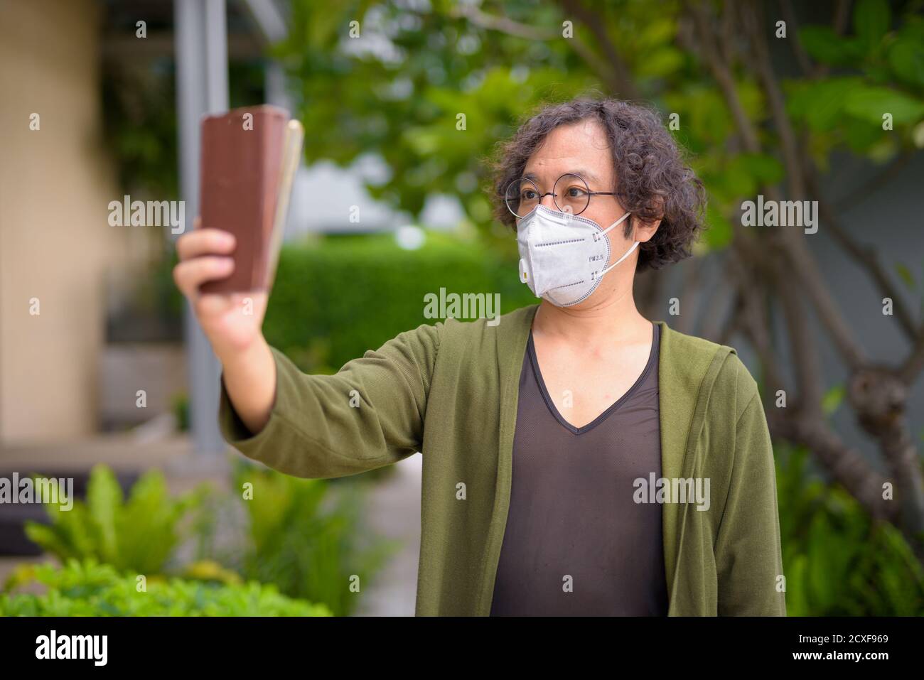 Uomo giapponese con maschera che prende selfie nel giardino sul tetto Foto Stock