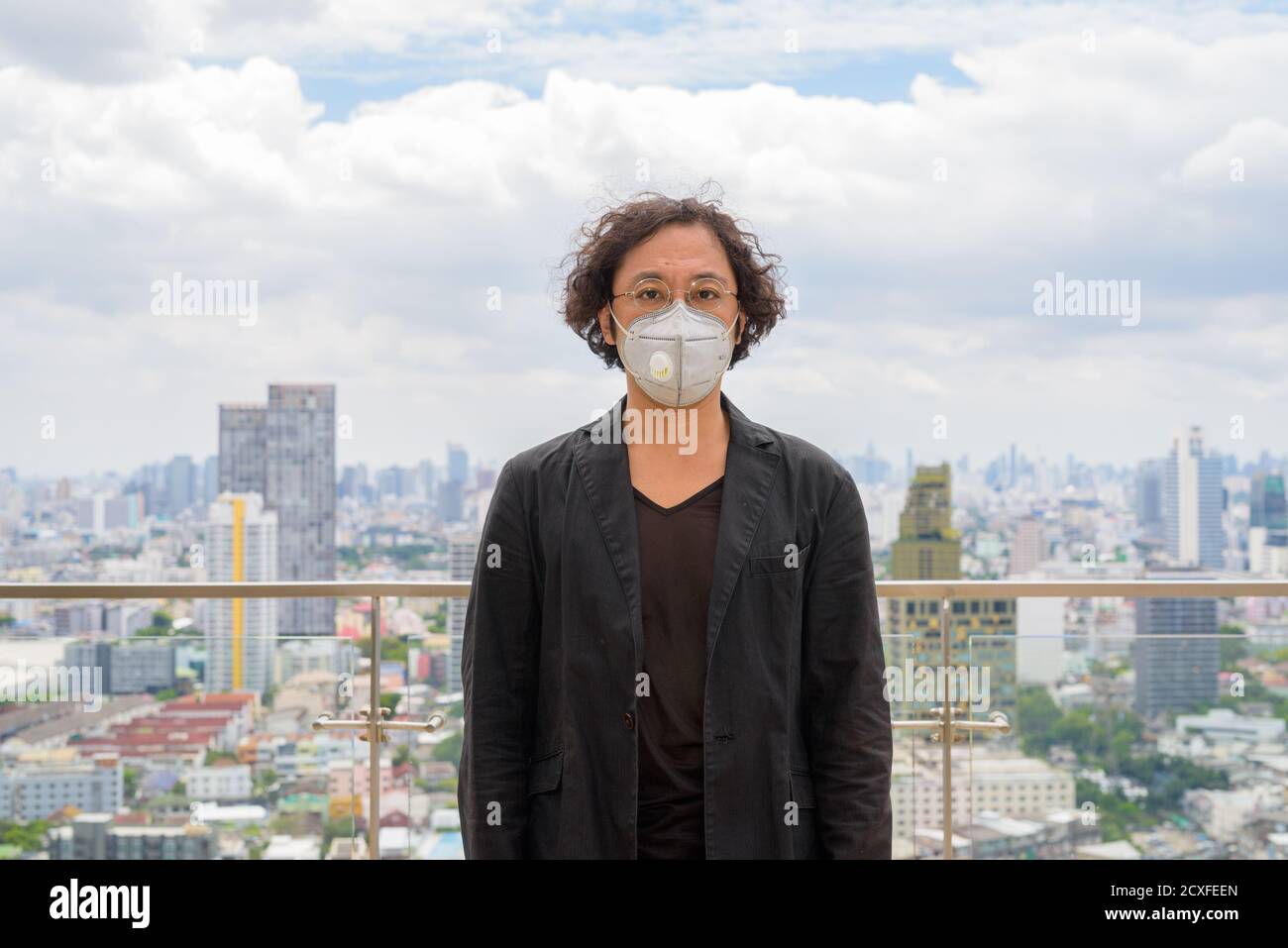 Ritratto di uomo d'affari giapponese indossare maschera contro la vista del città Foto Stock