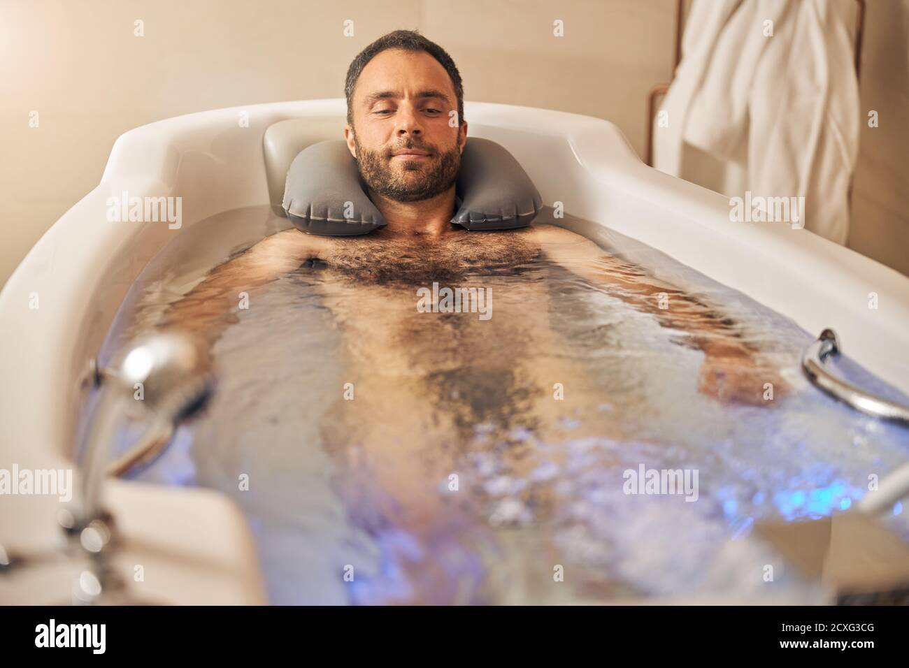 Bel giovane uomo che prende il bagno nel salone termale Foto Stock