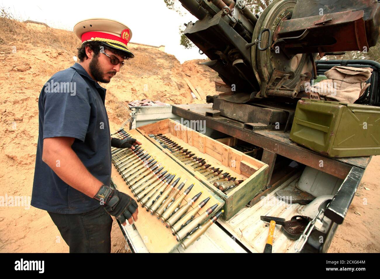 Un combattente ribelle libico prepara munizioni antiaeree mentre indossa il  cappello di un ufficiale pro-Muammar Gheddafi sulla linea di fronte  occidentale di Misrata, a circa 25 km (16 miglia) dal centro della