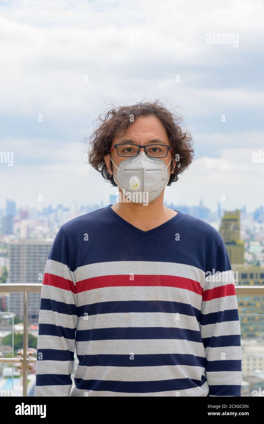 Ritratto dell'uomo giapponese che indossa una maschera contro la vista del città Foto Stock