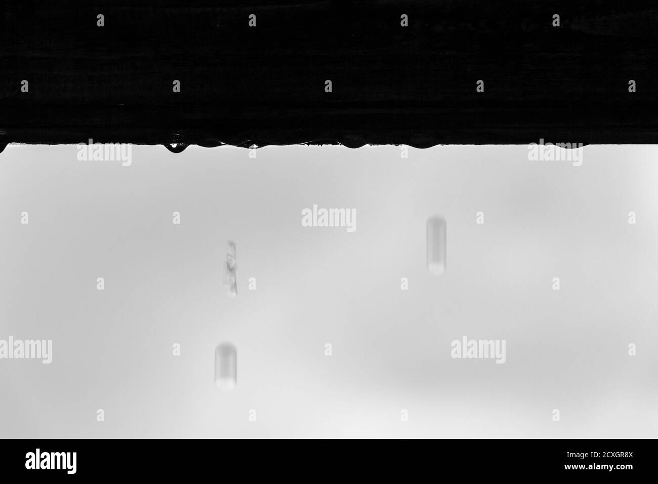 L'acqua gocciola dal tetto di una casa durante la pioggia. Foto Stock