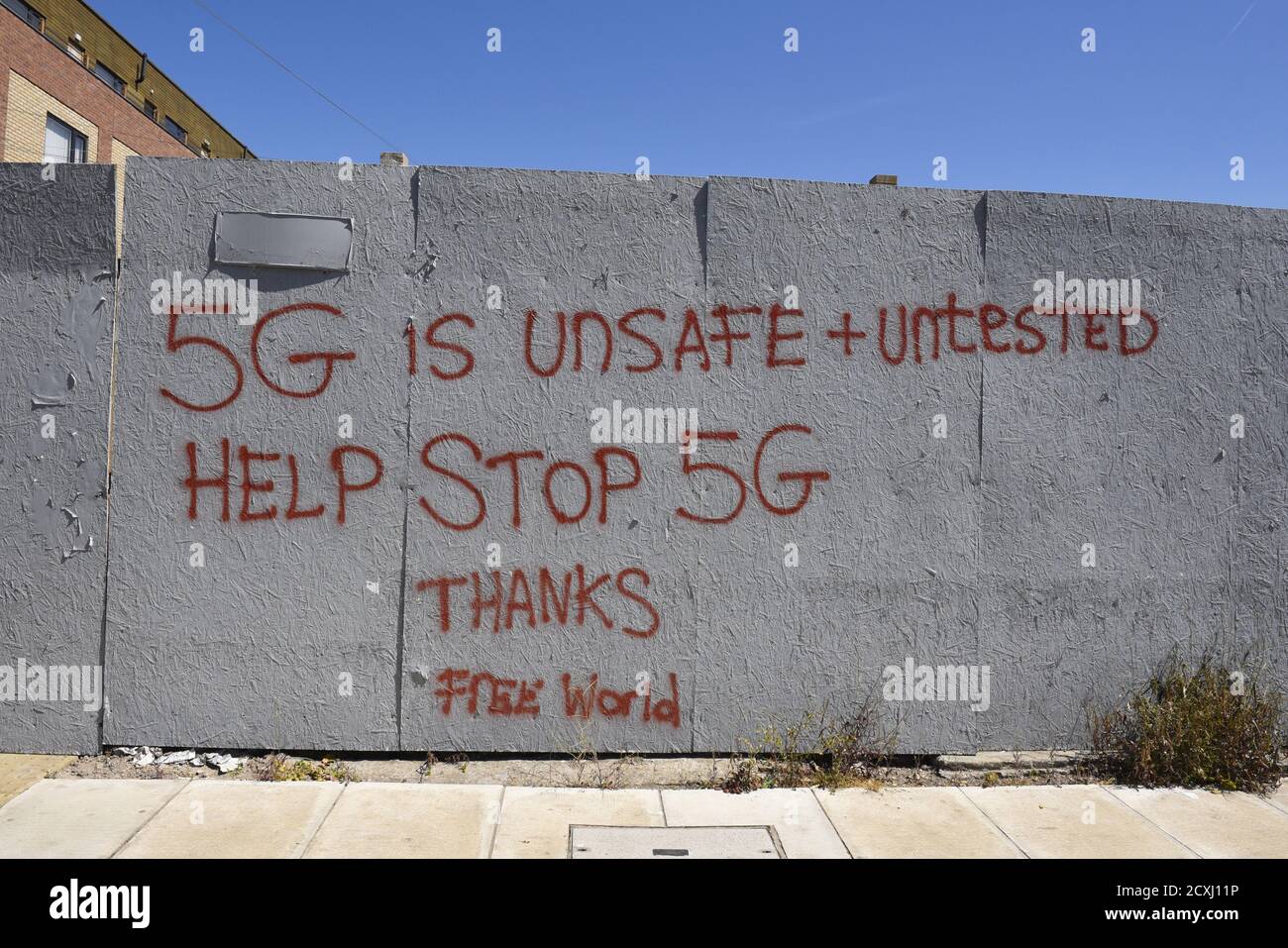 Graffiti circa 5G - '5G è non sicuro e non testato, aiutare a fermare 5G grazie, mondo libero' vernice rossa su una faccia di legno grigio. Foto Stock