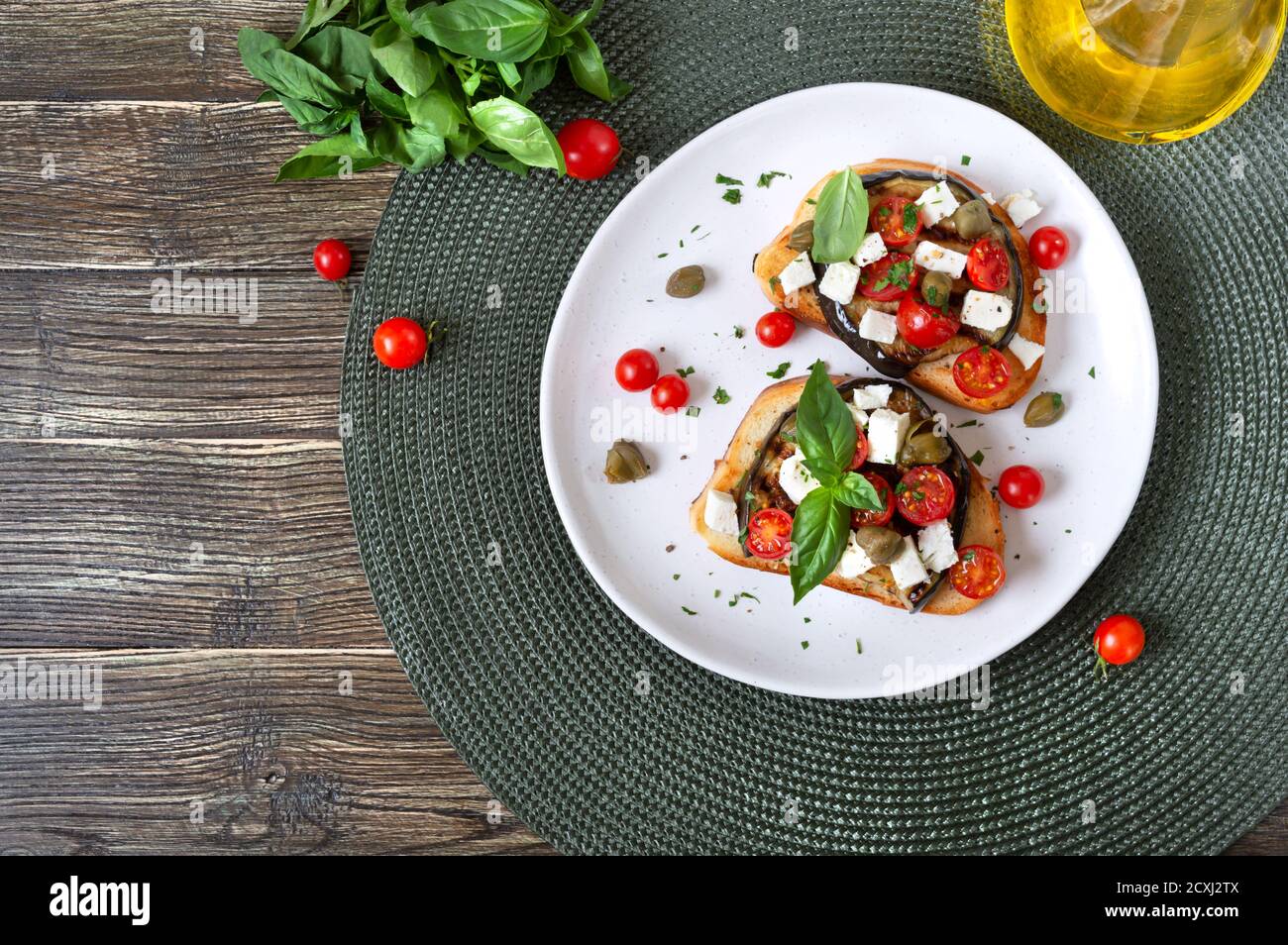 Bruschetta all'aglio con melanzane, feta, pomodori ciliegini, capperi. Utile antipasto vegetariano. Cucina italiana. Vista dall'alto Foto Stock