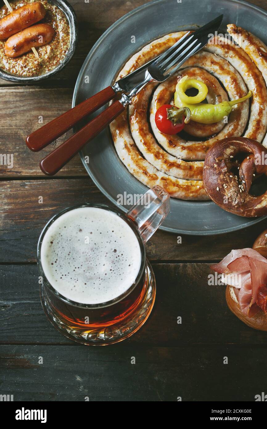 Grande spirale salsicce fritte, carne spuntini wienerwurst, prosciutto, marinato al peperoncino servito in salati salatini e la piastra con un bicchiere di birra chiara e musta Foto Stock