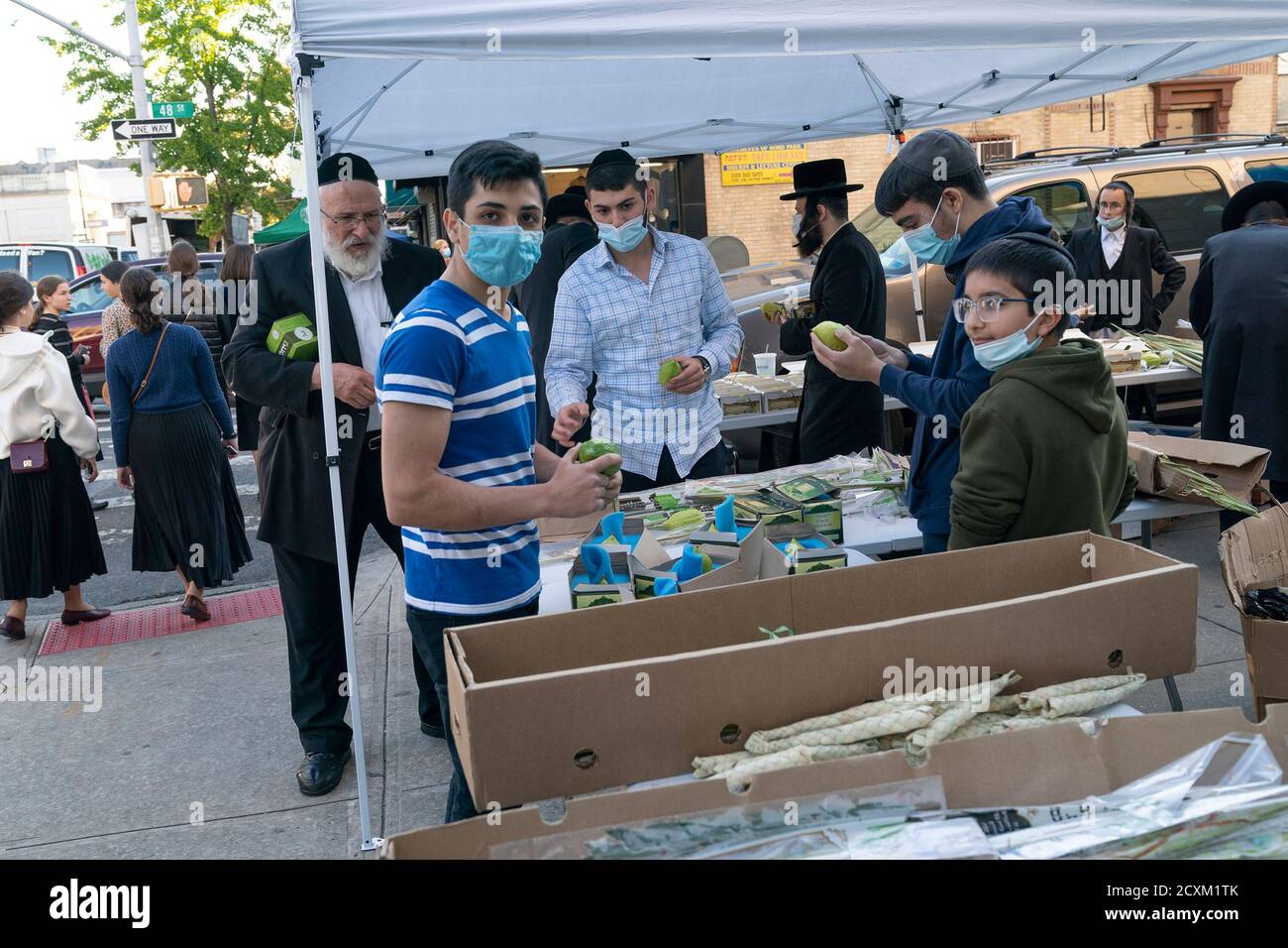 NYC cercando di crack down sulla maschera indossando in zone dove picco in casi positivi rilevati a Brooklyn. I funzionari della città preoccupati per i picchi nelle comunità ortodosse prevalentemente ebraiche hanno iniziato a distribuire maschere gratuite e disinfettanti per le mani, nonché volantini per combattere un numero crescente di casi positivi COVID-19. Molte altre persone hanno iniziato a indossare maschere, ma alcuni ancora si rifiutano di farlo, anche all'interno. Mentre Sukkot Holiday si sta avvicinando la gente sta comprando gli attributi come le foglie di palma, ramo di salice albero, etrog e maturo, verde, fronte chiuso da un albero di palma di data sul mercato di strada aperto. (Foto di Foto Stock