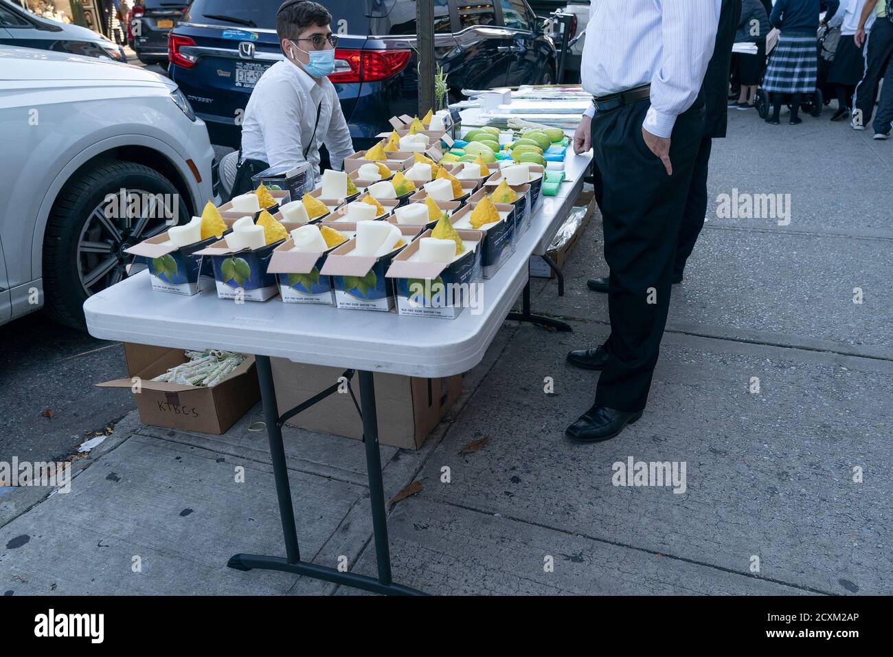 NYC cercando di crack down sulla maschera indossando in zone dove picco in casi positivi rilevati a Brooklyn. I funzionari della città preoccupati per i picchi nelle comunità ortodosse prevalentemente ebraiche hanno iniziato a distribuire maschere gratuite e disinfettanti per le mani, nonché volantini per combattere un numero crescente di casi positivi COVID-19. Molte altre persone hanno iniziato a indossare maschere, ma alcuni ancora si rifiutano di farlo, anche all'interno. Mentre Sukkot Holiday si sta avvicinando la gente sta comprando gli attributi come le foglie di palma, ramo di salice albero, etrog e maturo, verde, fronte chiuso da un albero di palma di data sul mercato di strada aperto. (Foto di Foto Stock