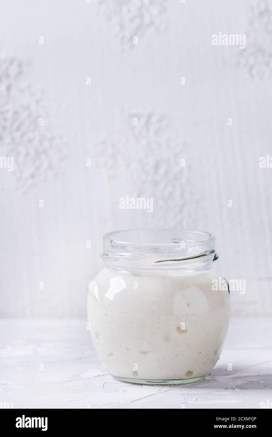 Pasta di base di grano in vasi di vetro per cuocere il pane fatto in casa su fondo grigio di cemento. Foto Stock