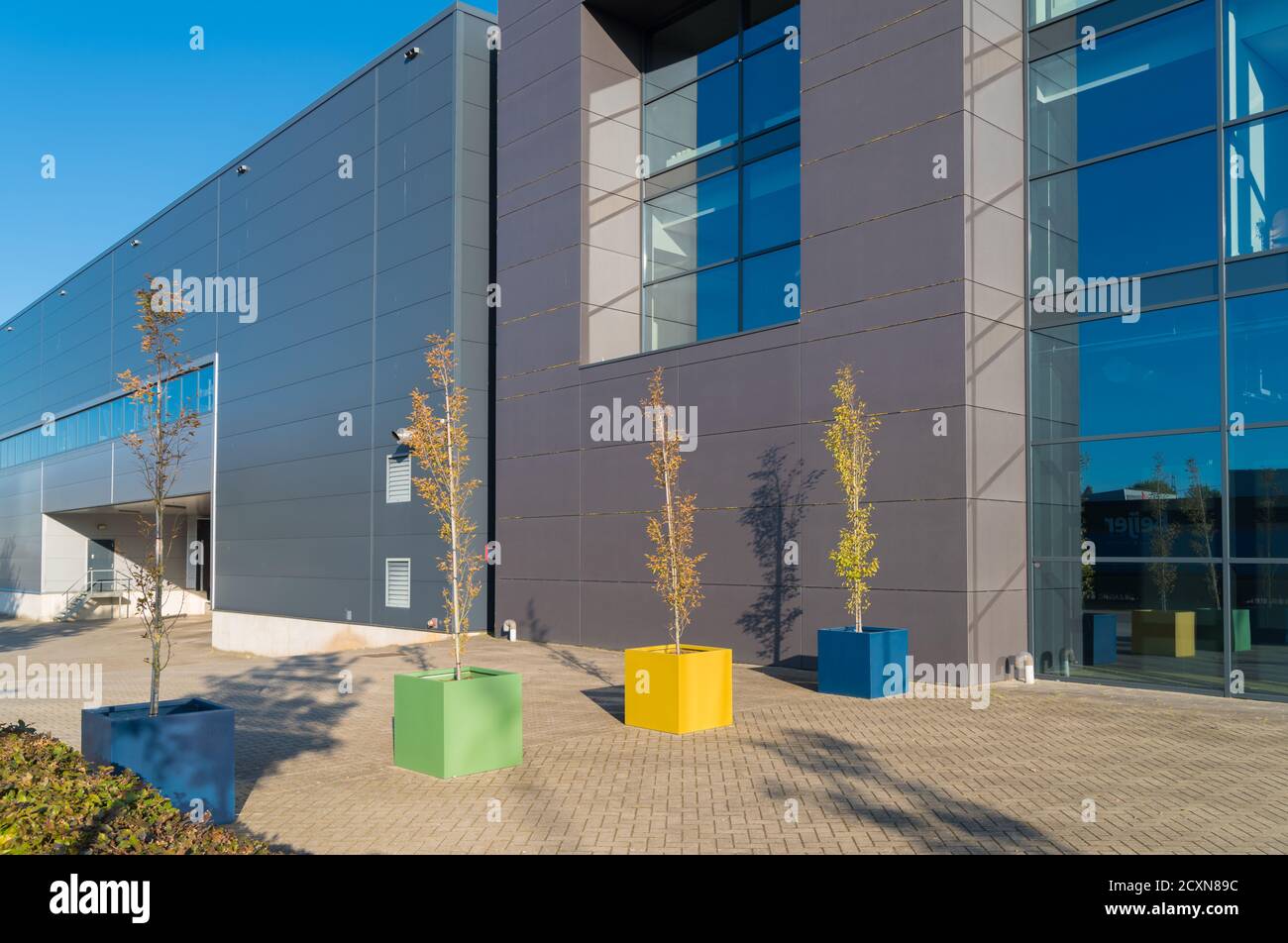 esterno di un moderno edificio di uffici in vetro con piantatrici colorate davanti Foto Stock