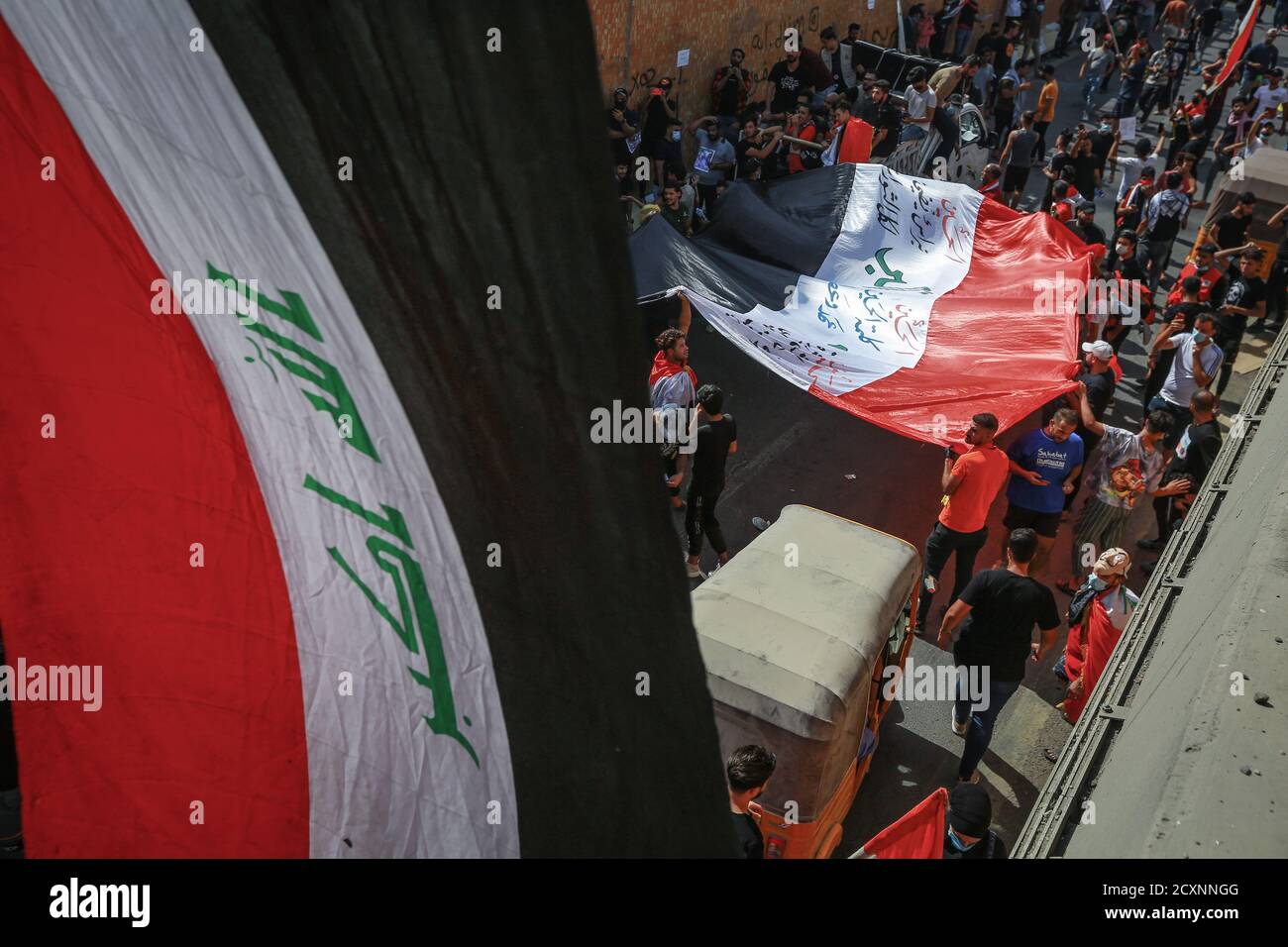 Baghdad, Iraq. 01 Ottobre 2020. I manifestanti iracheni detengono una bandiera nazionale durante una protesta, per celebrare il primo anniversario delle manifestazioni anti-governative. Credit: Ameer al Mohammedaw/dpa/Alamy Live News Foto Stock