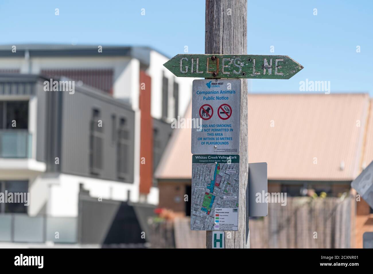 Un cartello di avvertenza per non fumatori e non cani si trova sotto un vecchio cartello in legno con il nome di una strada vicino a un parco per bambini Nel sobborgo di Sydney di Annandale in Australia Foto Stock