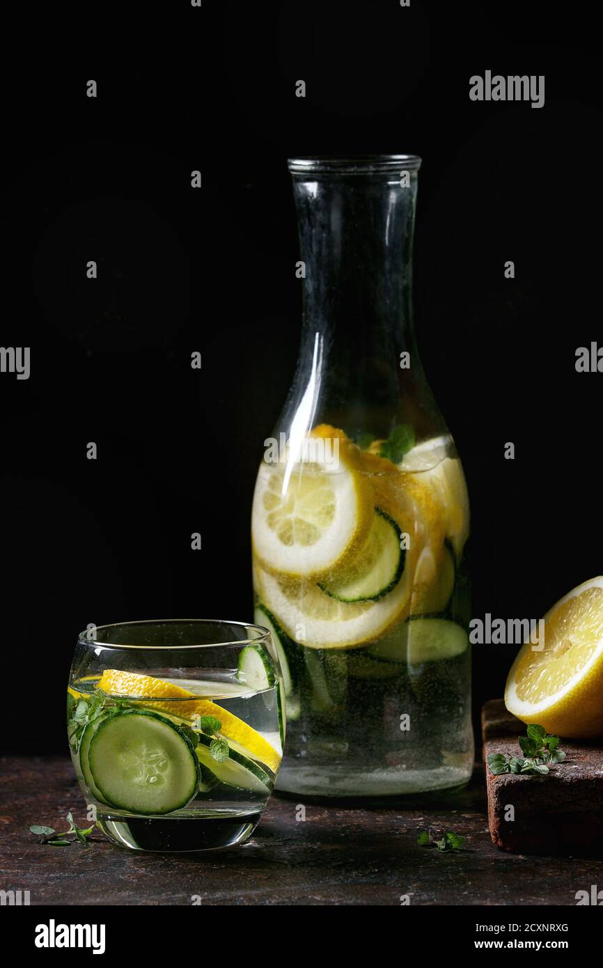 Bacche di cetrioli di agrumi, mirtillo e raspberry sassy acqua sassi per disintossicare in bottiglie di vetro su fondo nero scuro. Cibo pulito, stile di vita sano Foto Stock