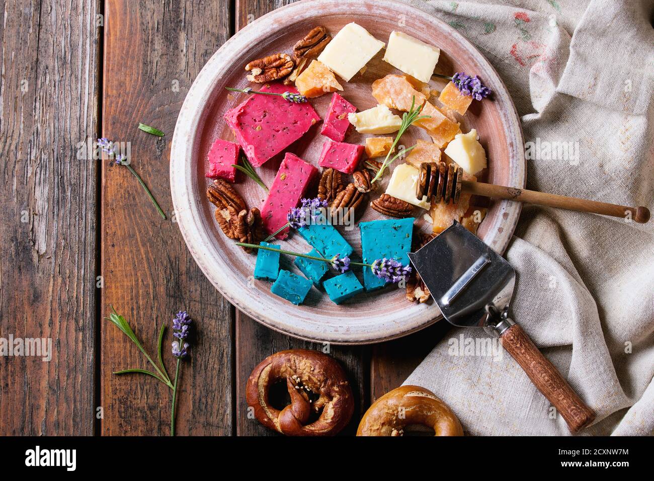 Varietà di coloratissimi holland tradizionale formaggio morbido, vecchio, basilico rosa, blu lavanda servita con noci pecan, miele, fiori di lavanda, salatini pane su Foto Stock