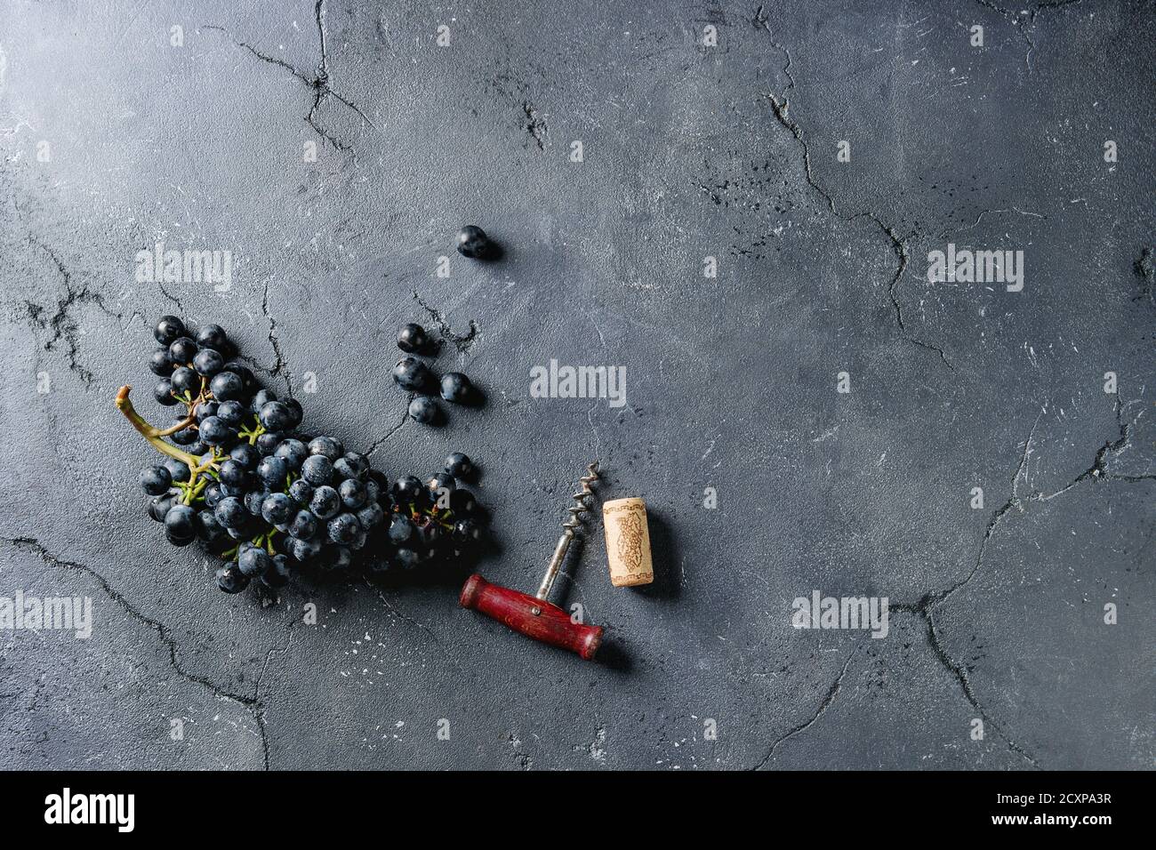 Mazzetto di fresche e mature blu scuro Isabella uve con la vecchia struttura di cavatappi e sughero nero su sfondo di texture. Vista da sopra con lo spazio. Sfondo di cibo Foto Stock