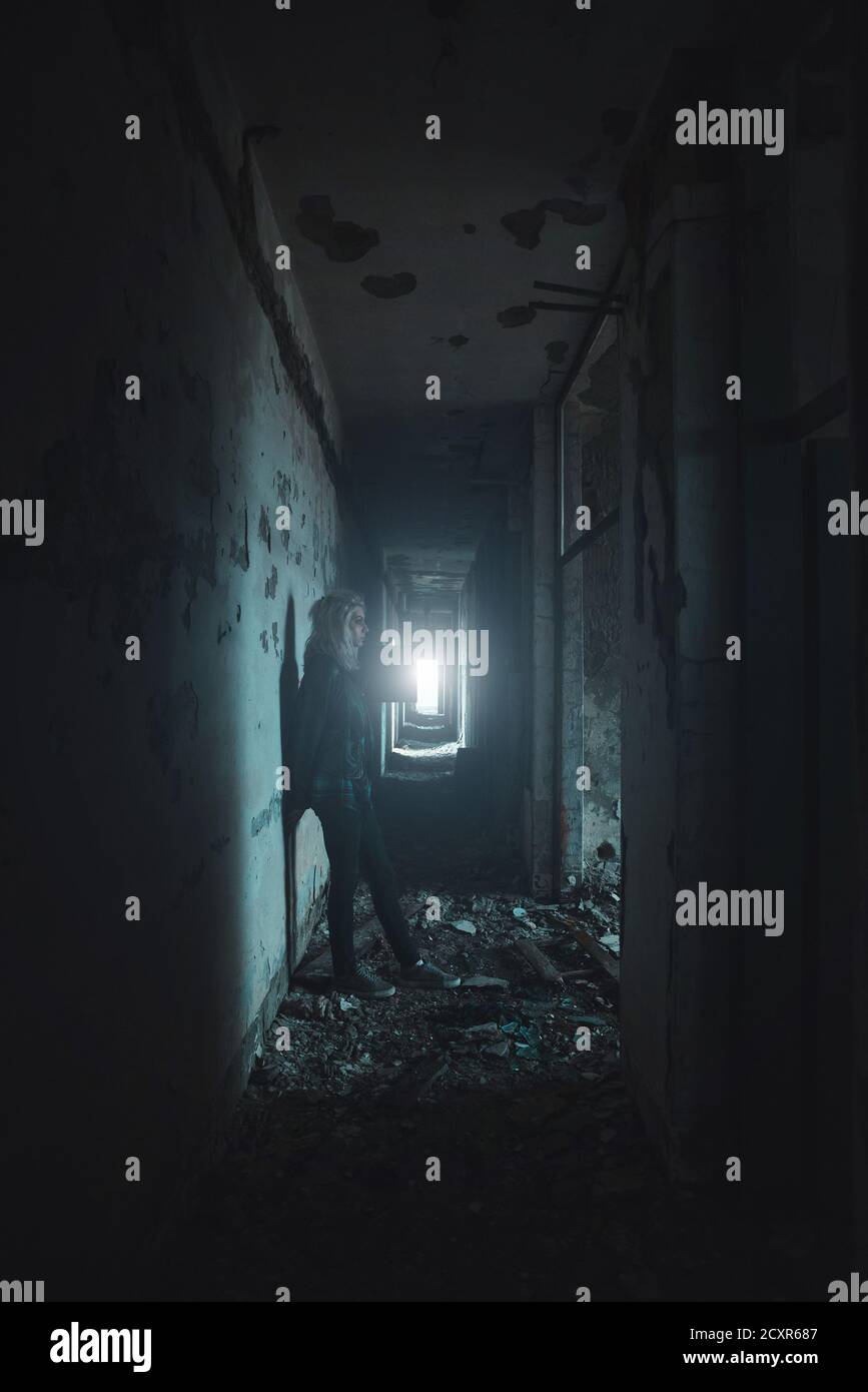 Giovane donna in piedi nel concetto di orrore di sala oscura Foto Stock