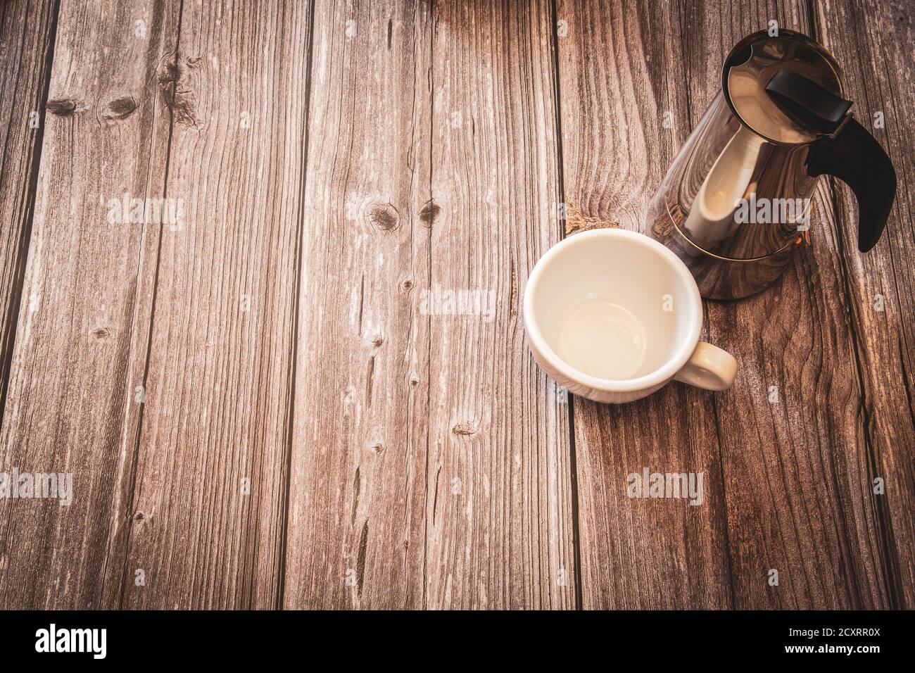 Una caffettiera argentata e una tazza di caffè bianca su un rustico sfondo in legno con spazio copia Foto Stock