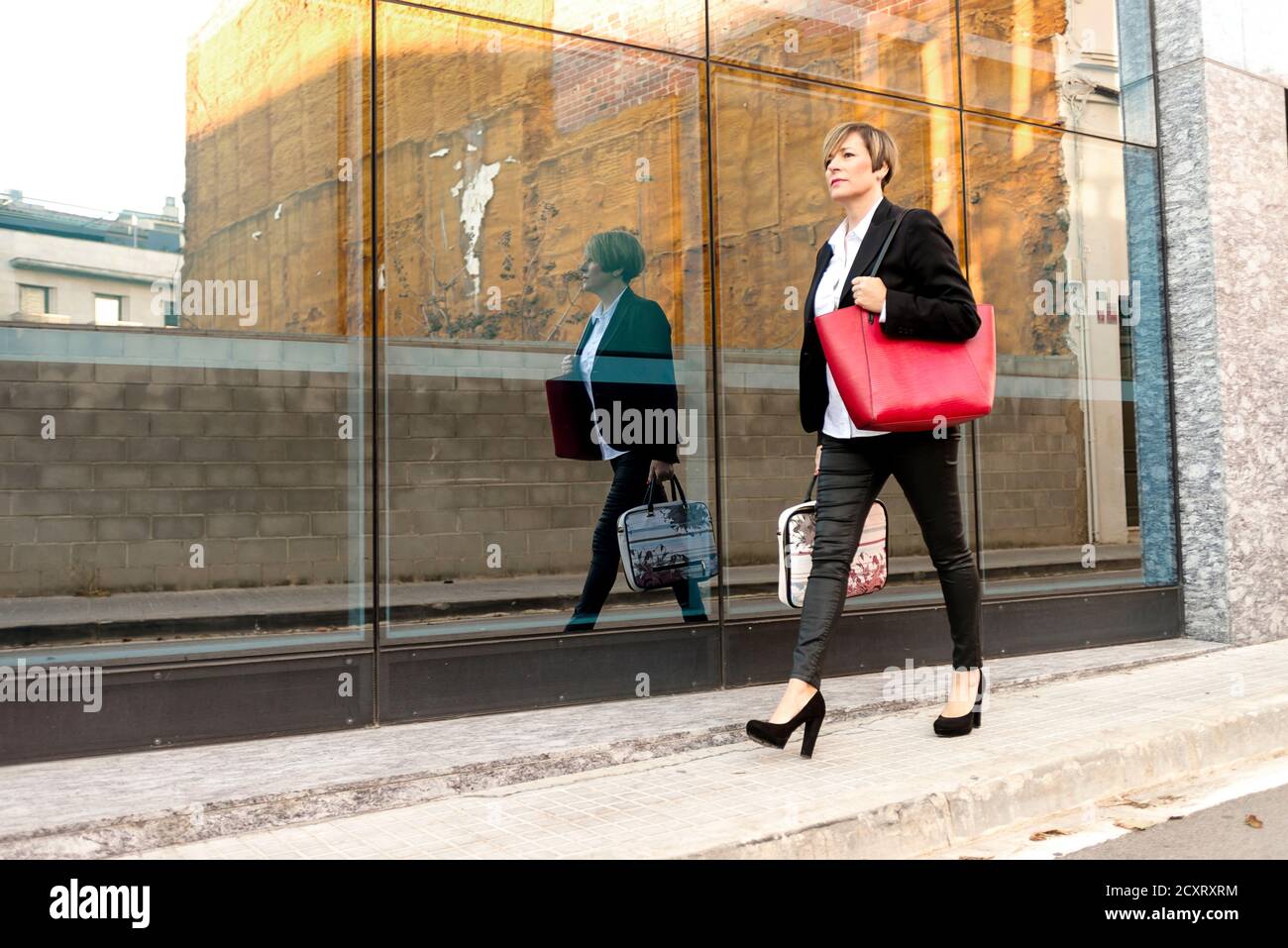 Donna che cammina con la borsa di un computer portatile accanto all'edificio dell'ufficio Foto Stock