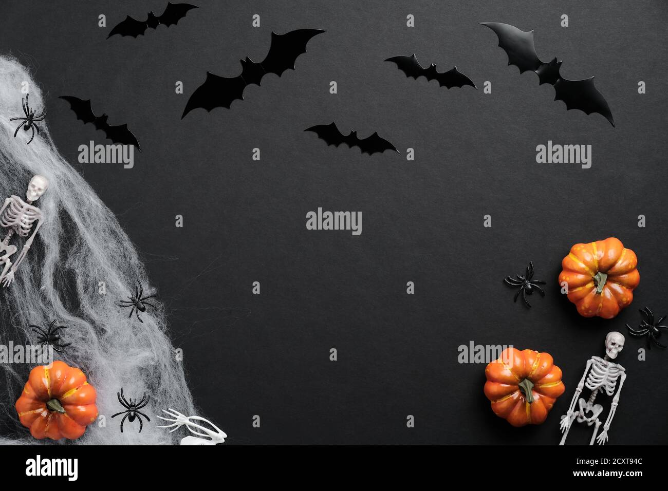 Concetto felice di festa di Halloween. Pipistrelli silhouette, zucche, ragnatela, scheletri, ragni su sfondo nero. Carta di Halloween. Foto Stock