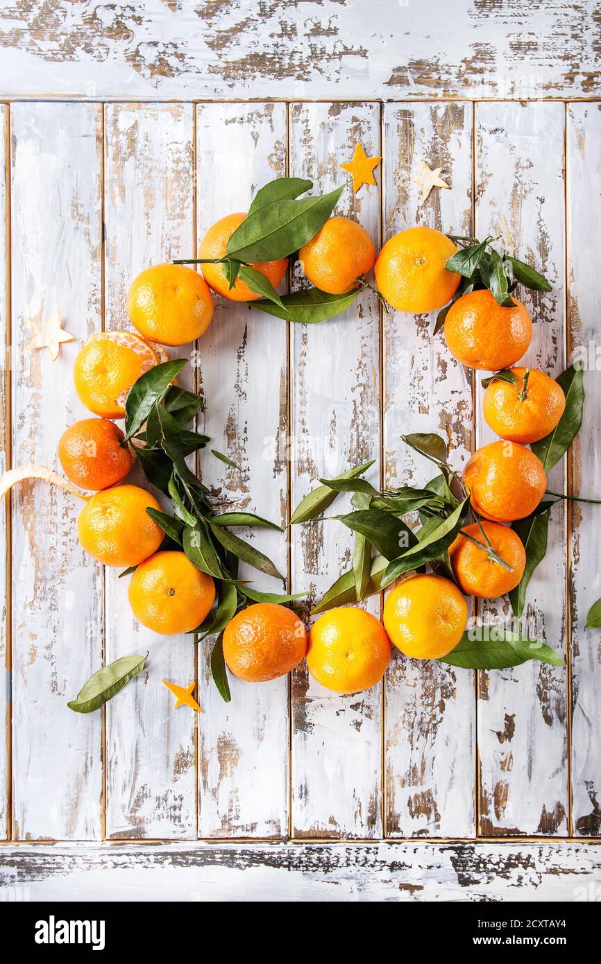 Clementine tangerini con foglie come corona di Natale su sfondo bianco tavola di legno. Vista dall'alto, spazio. Biglietti e decorazioni per il nuovo anno. Foto Stock