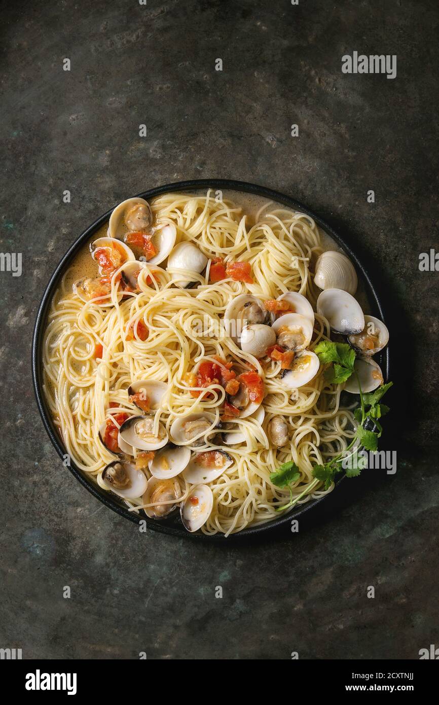 Pasta Spaghetti vongole in crema di pomodoro in salsa di piastra nera sopra il vecchio metallo sfondo texture. Vista superiore, spazio Foto Stock