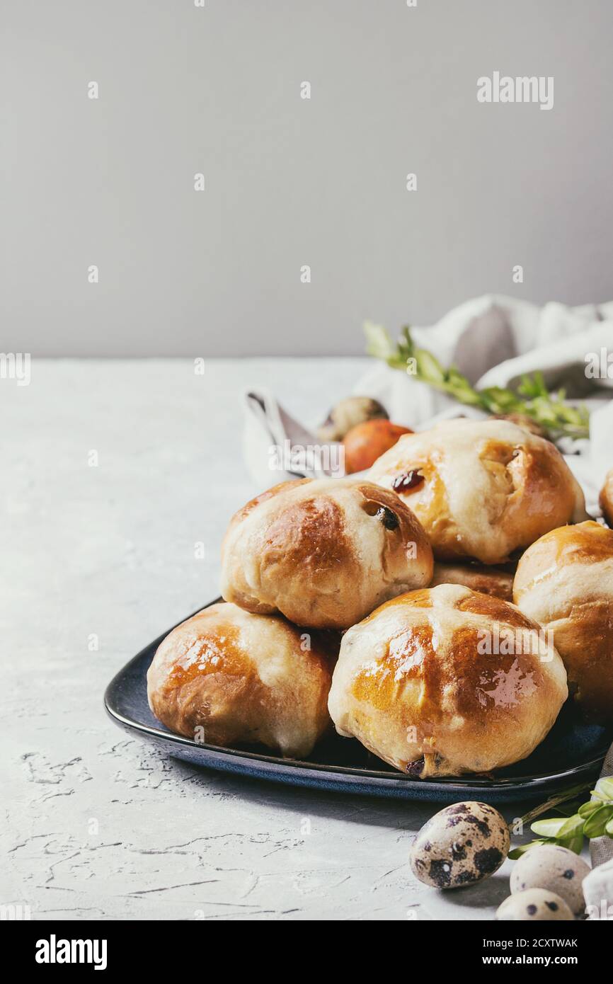 Pasqua in casa calde tradizionali ciambelle a croce sulla piastra di blu con tessili colorate e uova di quaglia su bianco sullo sfondo di texture. Copia dello spazio. Immagine dai toni Foto Stock