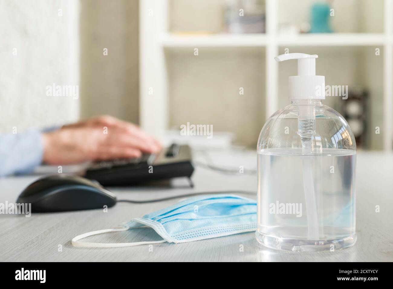 Dispenser di gel antibatterico con maschera chirurgica sulla scrivania dell'ufficio Foto Stock