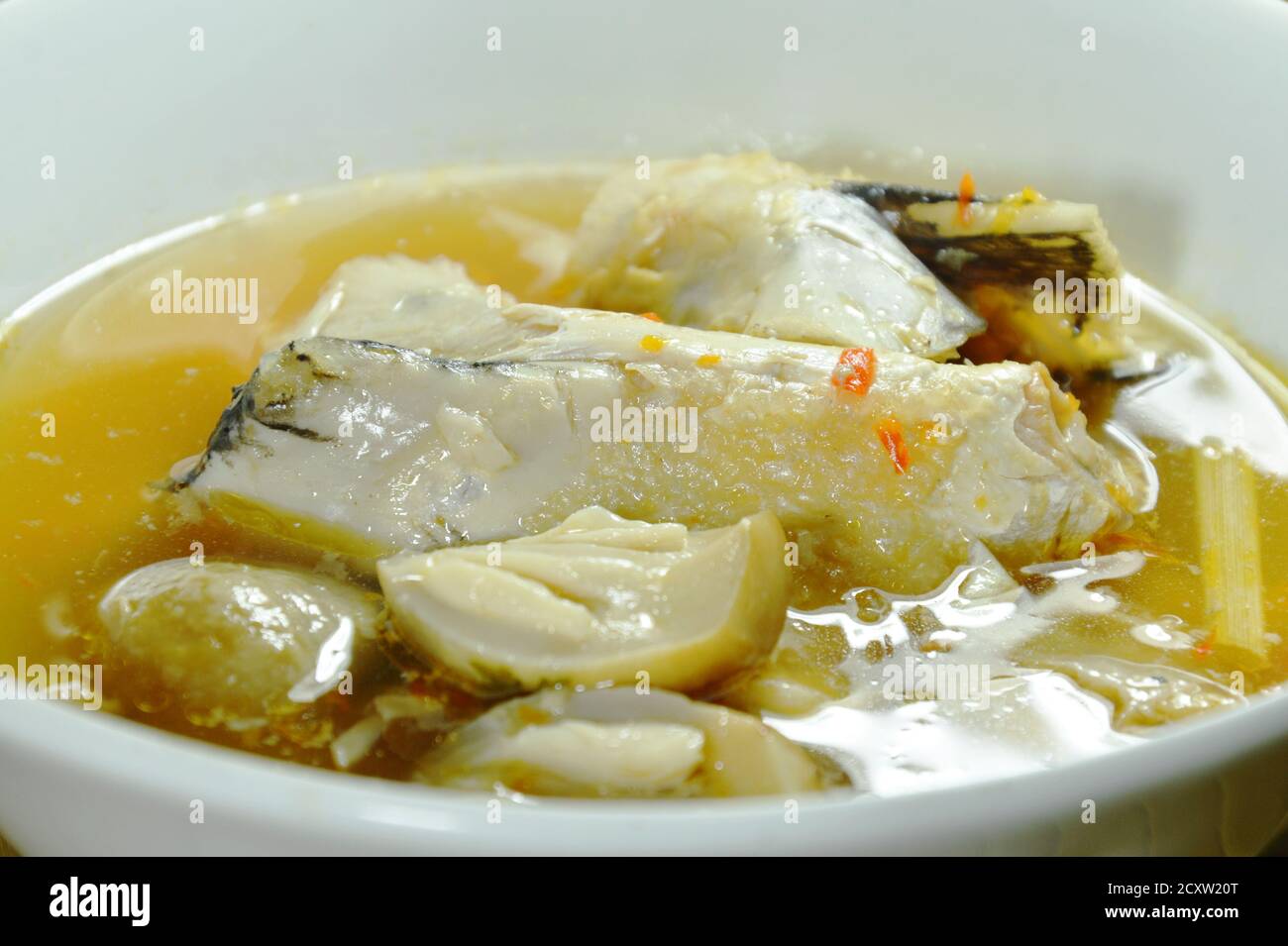 testa di pesce di salmone e funghi di paglia in zuppa di tom yum sul recipiente Foto Stock